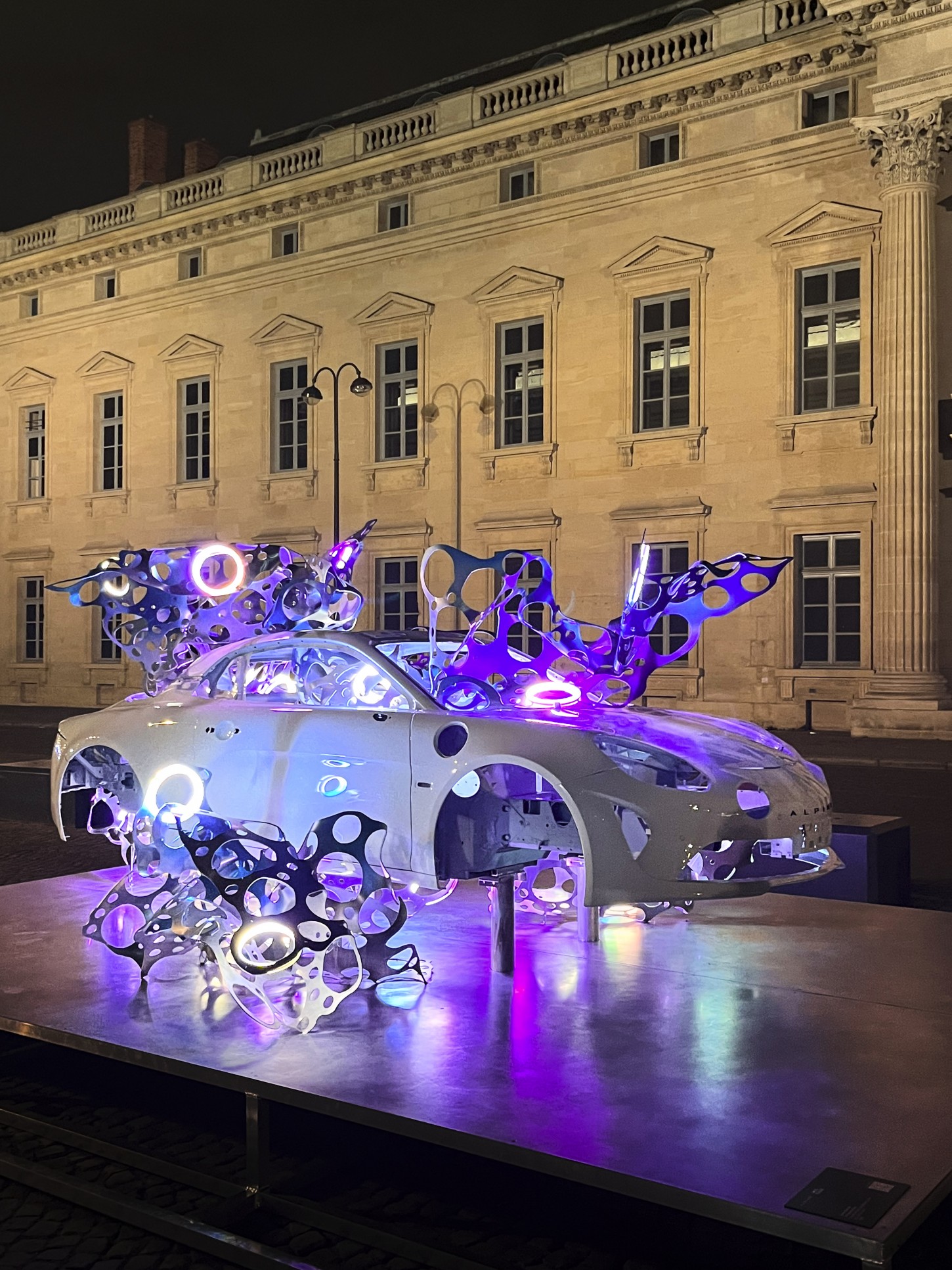 An illuminated Art car in front of the Palais Ephémère at Art Paris